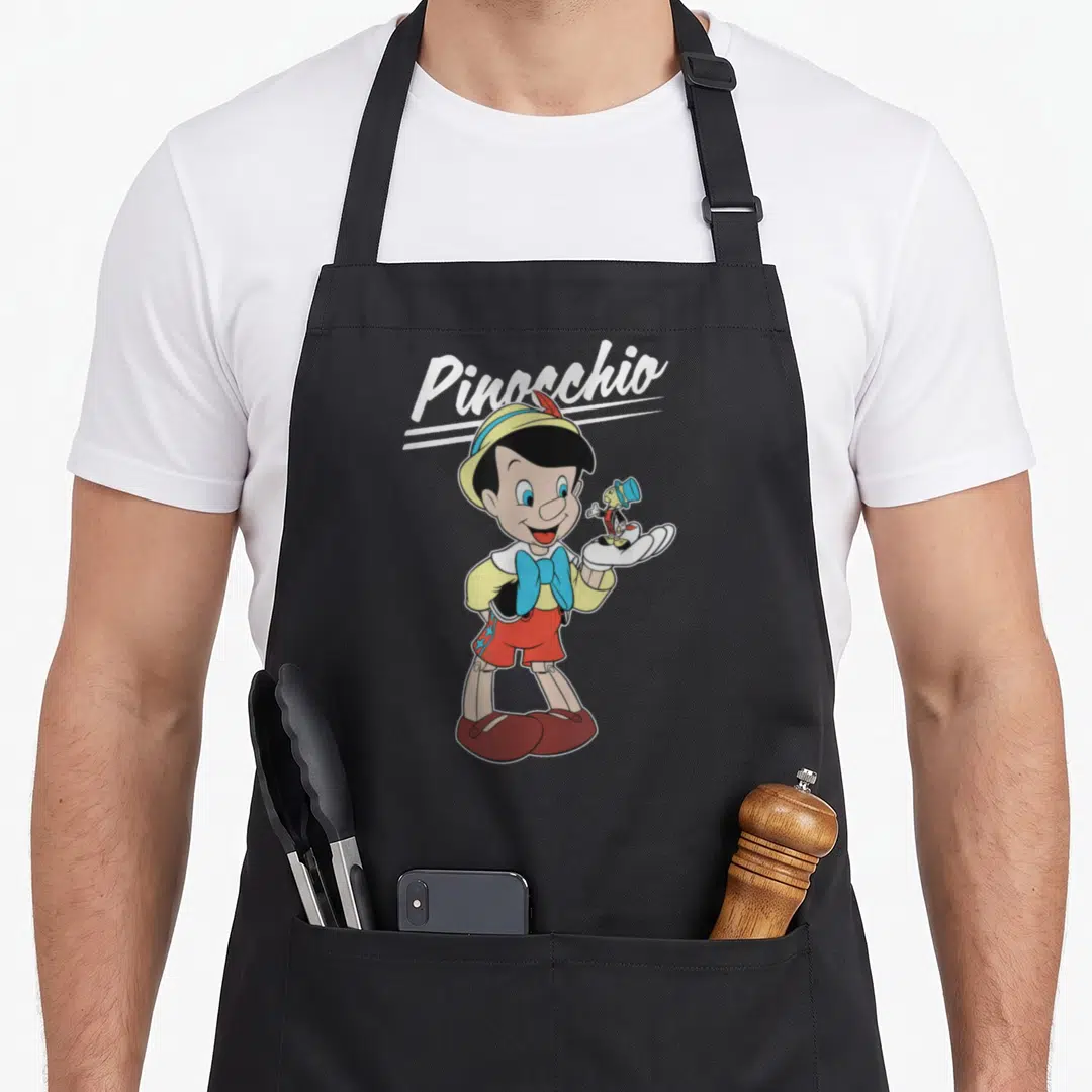Pinocchio jiminy cricket apron - Cartoon Pinocchio holding Jiminy Cricket in hand with white script text above — shown on a black cotton canvas apron against a white background