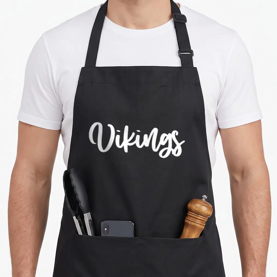 Viking sports team aprons - White cursive text reading Vikings on dark background — shown on a black cotton canvas apron against a white background