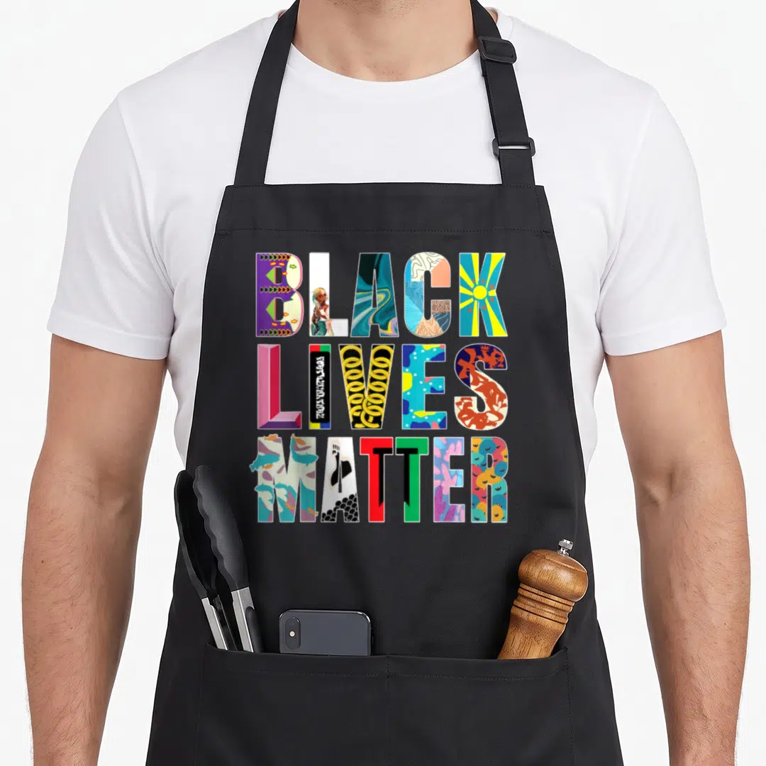 Live celebrate diversity apron - Stacked BLACK LIVES MATTER text letters filled with colorful unique illustrations — shown on a black cotton canvas apron against a white background