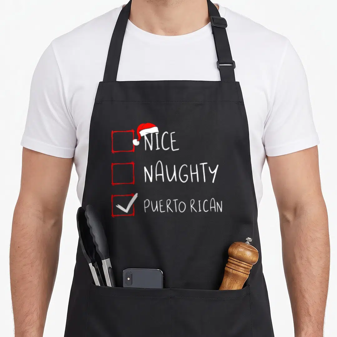 Puerto christmas apron - Nice Naughty Puerto Rican checklist with red boxes, white checkmark, and Santa hat — shown on a black cotton canvas apron against a white background
