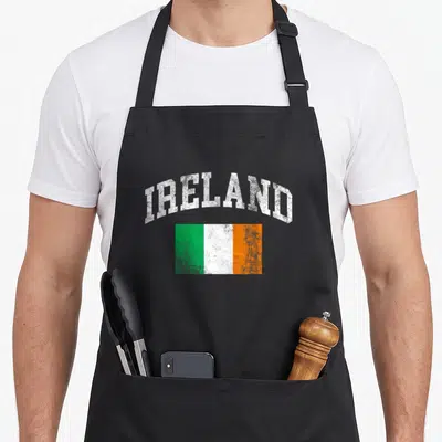 Irish flag ireland apron - Arched IRELAND text above distressed green white and orange rectangular flag — shown on a black cotton canvas apron against a white background