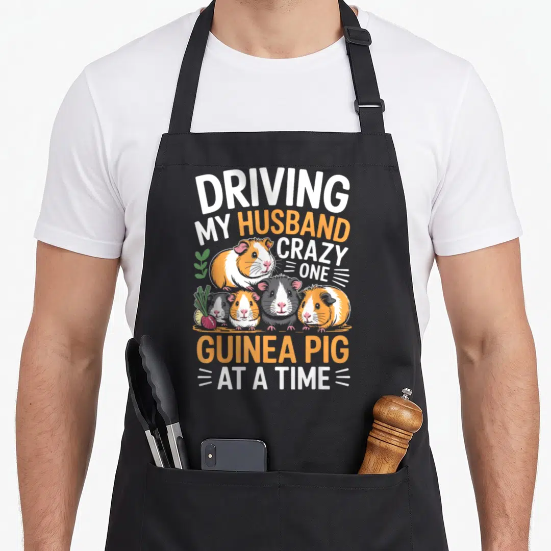 Pet driving apron - Five cartoon guinea pigs with carrot and radish surrounded by stacked text in orange and white — shown on a black cotton canvas apron against a white background