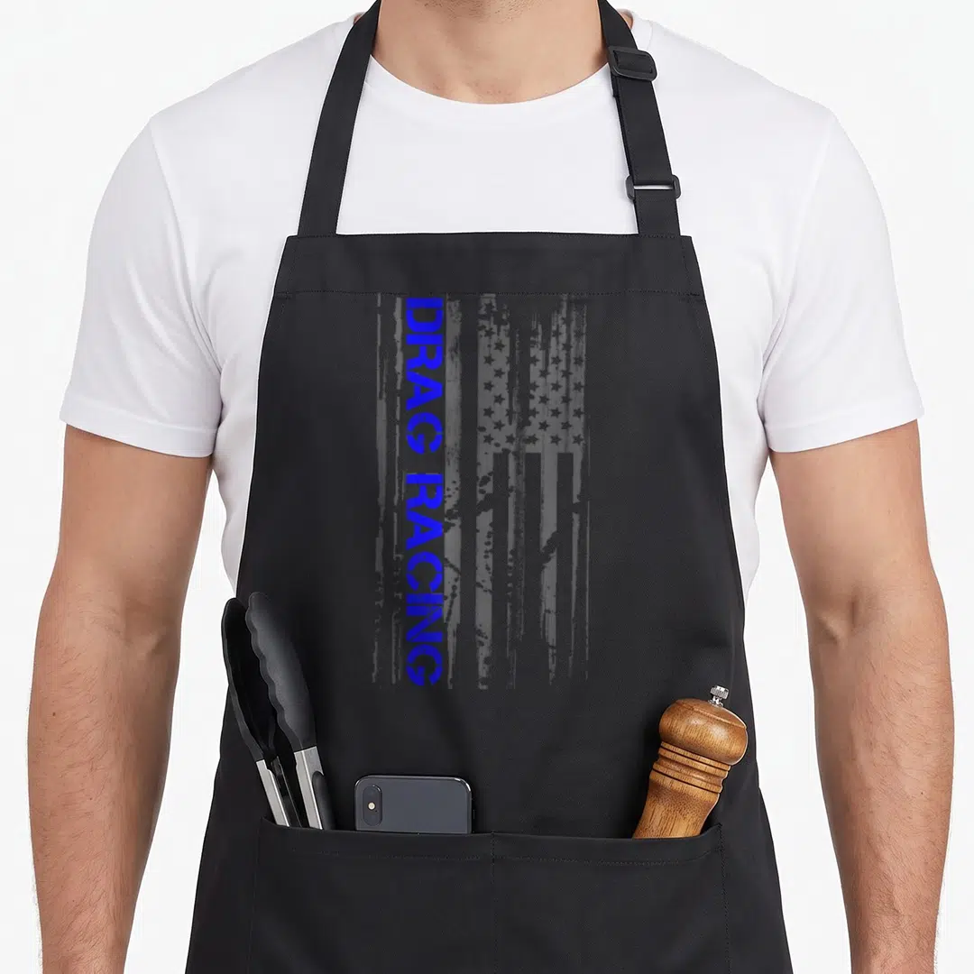 Drag american flag apron - Vertical blue DRAG RACING text over distressed white flag pattern — shown on a black cotton canvas apron against a white background