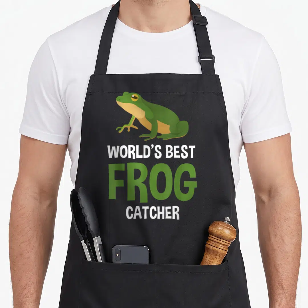Catcher frog aprons - Green cartoon frog above white and green text reading WORLD'S BEST FROG CATCHER — shown on a black cotton canvas apron against a white background