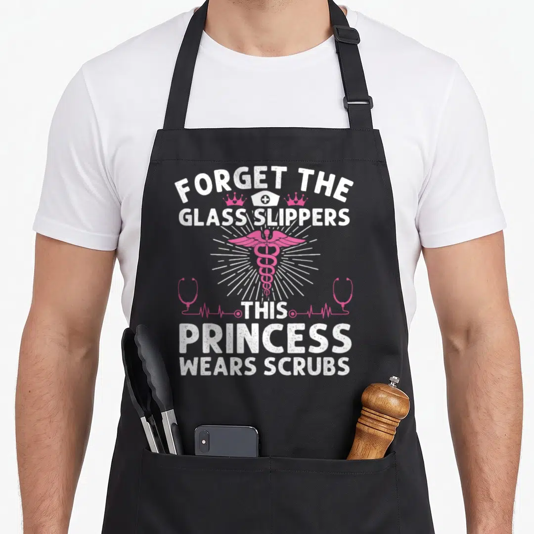 Princess nurse apron - Pink caduceus with white text Forget The Glass Slippers This Princess Wears Scrubs and two crowns — shown on a black cotton canvas apron against a white background