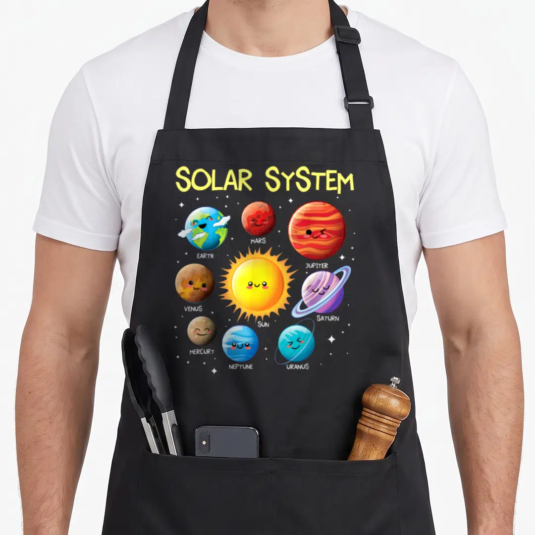 Solar teacher apron - Cartoon sun and planets Earth Mars Jupiter Venus Saturn Mercury Neptune Uranus with names below — shown on a black cotton canvas apron against a white background