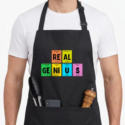 Element genius table apron - Six colored squares with element data spelling real genius typography design — shown on a black cotton canvas apron against a white background