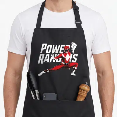 Action pose karate apron - Red Ranger in fighting stance with POWER RANGERS text and lightning bolt in red white black — shown on a black cotton canvas apron against a white background
