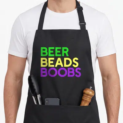 Beer fat chef apron - Stacked text reading BEER BEADS BOOBS in green yellow and purple block letters — shown on a black cotton canvas apron against a white background