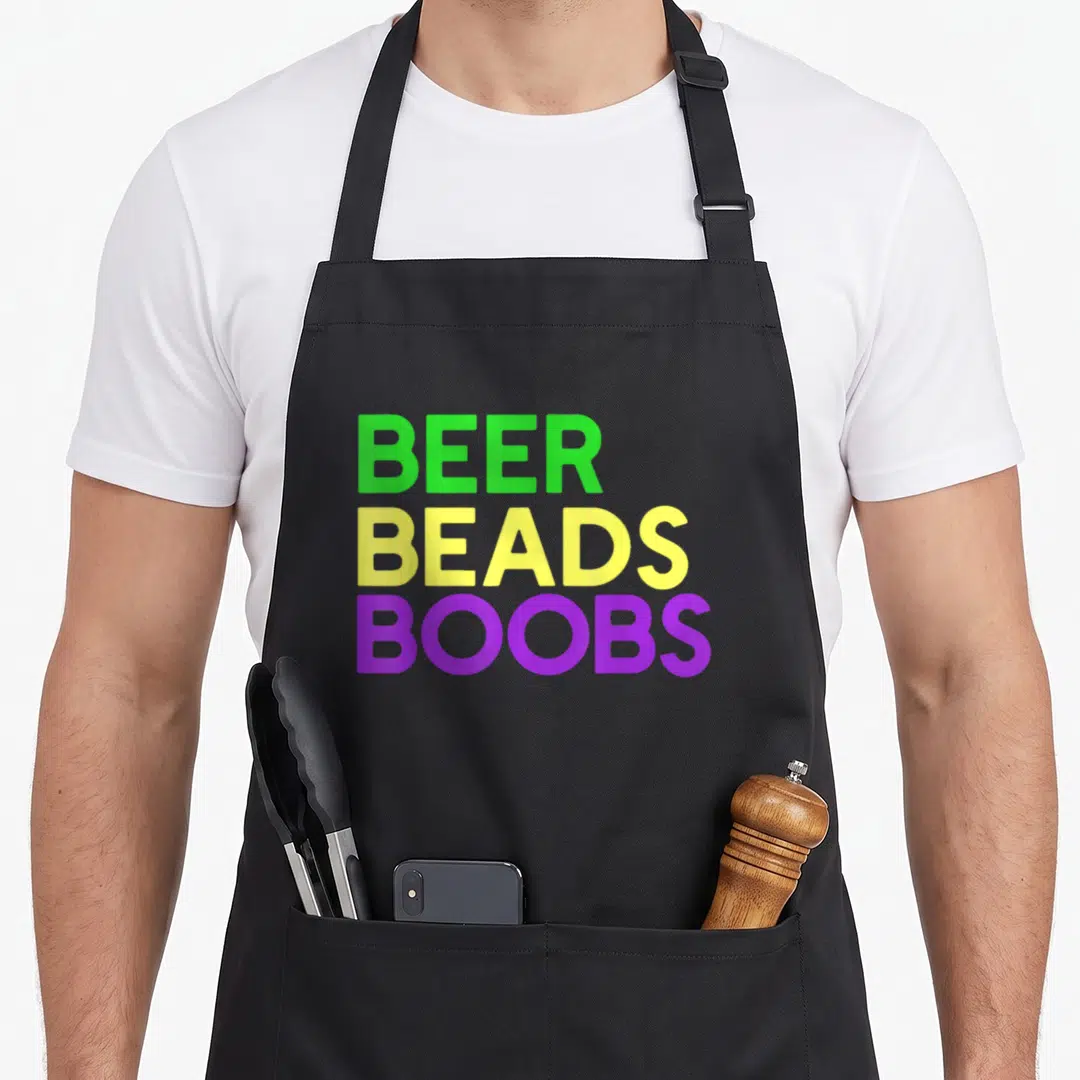 Beer fat chef apron - Stacked text reading BEER BEADS BOOBS in green yellow and purple block letters — shown on a black cotton canvas apron against a white background