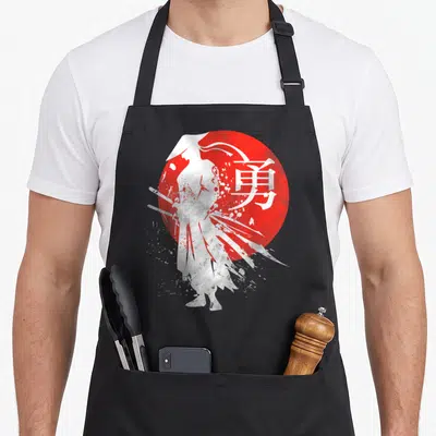 Warrior japan apron - White samurai silhouette standing before red sun with kanji character for courage — shown on a black cotton canvas apron against a white background