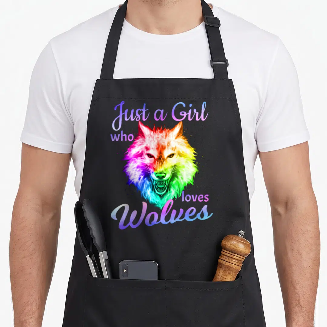 Moon wolf wolves apron - Rainbow wolf head surrounded by purple and blue script text reading Just a Girl who loves — shown on a black cotton canvas apron against a white background