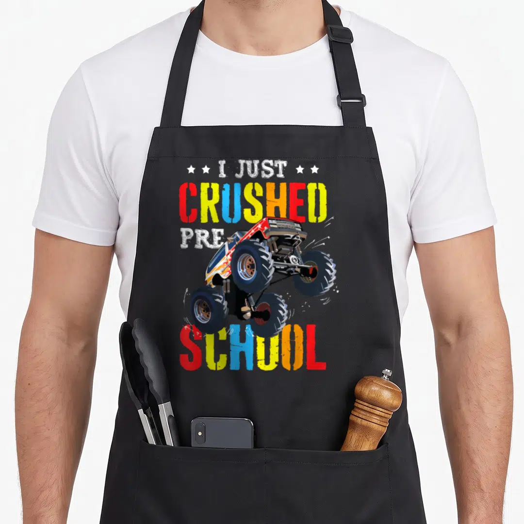 Preschool truck aprons - I Just Crushed Pre School monster truck cartoon with four stars and multicolored text — shown on a black cotton canvas apron against a white background