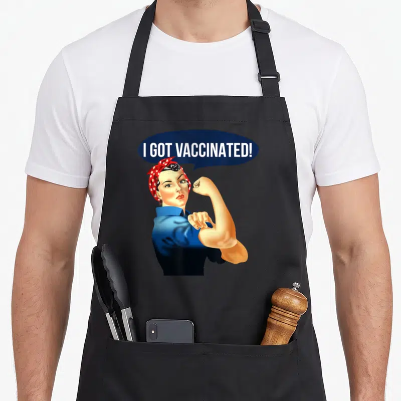 Pro rosie the riveter apron - Retro woman flexing arm below blue speech bubble reading I GOT VACCINATED in white text — shown on a black cotton canvas apron against a white background