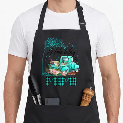 Mimi truck apron - Teal truck with pink flowers, butterflies, and black plaid MIMI text — shown on a black cotton canvas apron against a white background