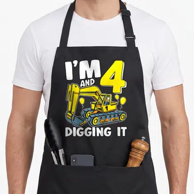 Digging 4th birthday apron - I'M 4 AND DIGGING IT text with yellow excavator and balloons — shown on a black cotton canvas apron against a white background
