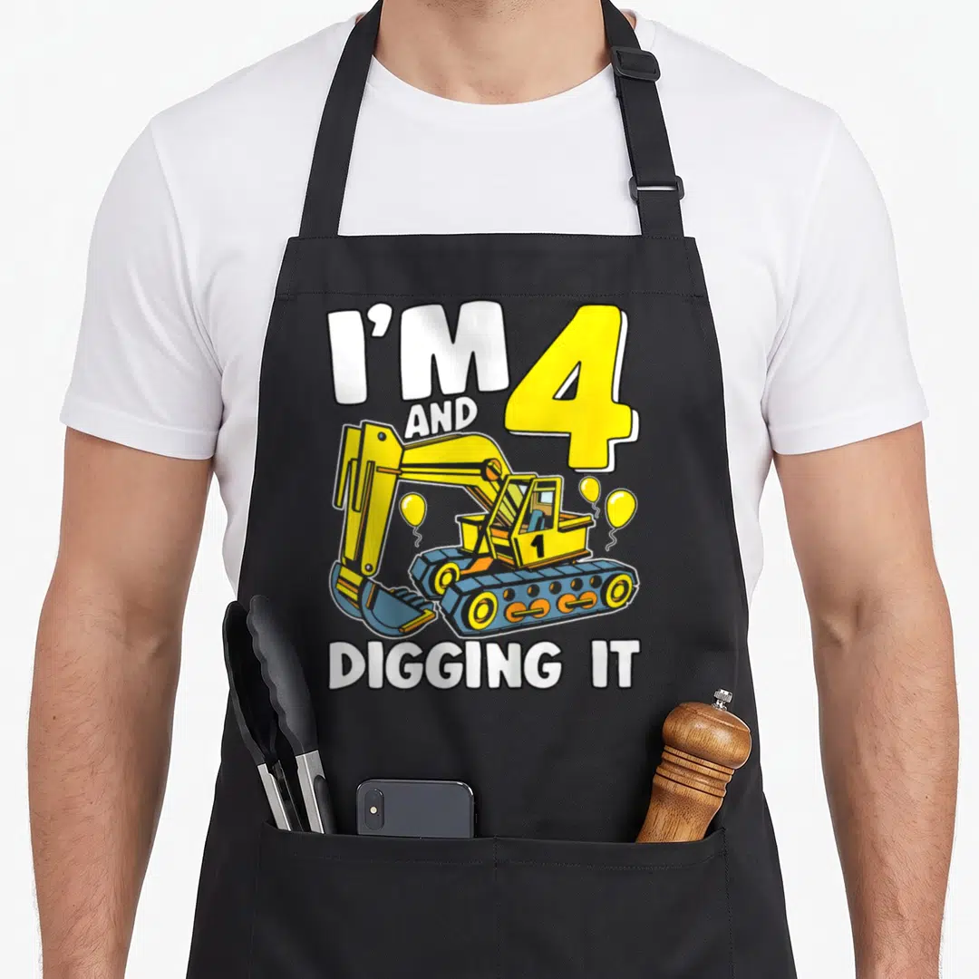 Digging 4th birthday apron - I'M 4 AND DIGGING IT text with yellow excavator and balloons — shown on a black cotton canvas apron against a white background