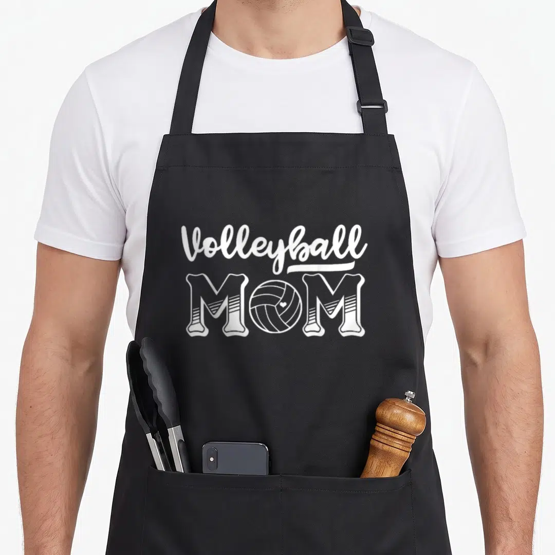Vintage volleyball apron - White MOM text with volleyball graphic replacing the O letter — shown on a black cotton canvas apron against a white background