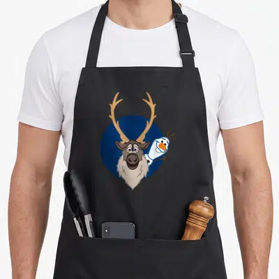 Sven frozen apron - Cartoon reindeer head with snowman peeking from behind on dark blue circle — shown on a black cotton canvas apron against a white background