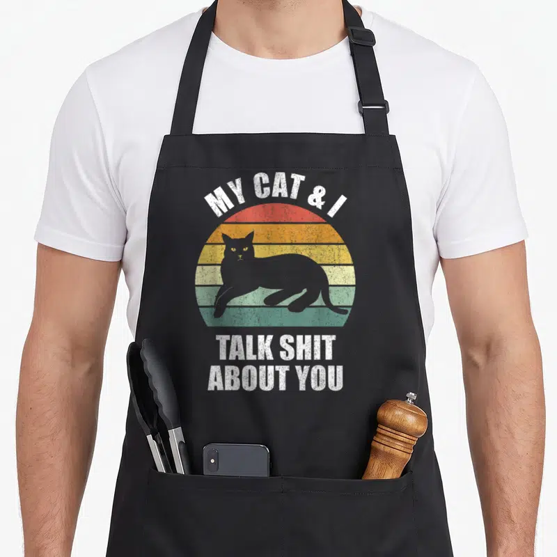 Funny talk cat apron - Retro sunset with grey cat silhouette and sarcastic white text — shown on a black cotton canvas apron against a white background