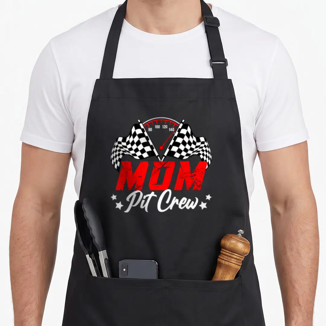 Car crew aprons - MOM Pit Crew speedometer with two crossed checkered flags and stars in red white black distressed — shown on a black cotton canvas apron against a white background