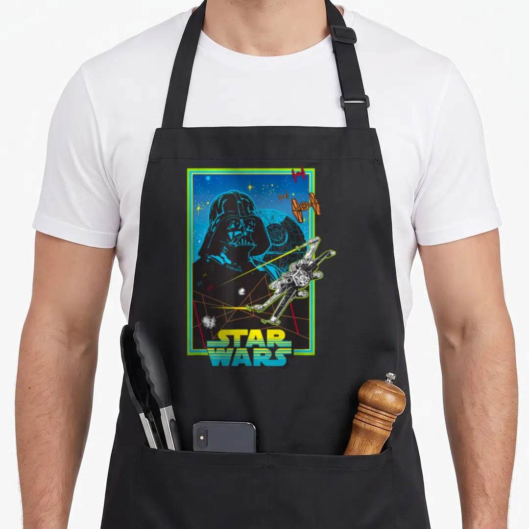 Hope 70s apron - Retro Darth Vader head with Death Star TIE fighters and stacked Star Wars logo — shown on a black cotton canvas apron against a white background