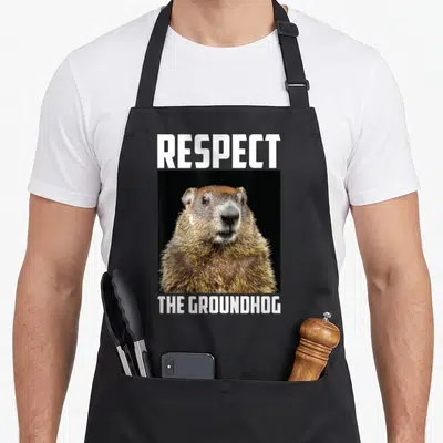 Respect groundhog apron - Photo of brown groundhog between white text RESPECT THE GROUNDHOG — shown on a black cotton canvas apron against a white background