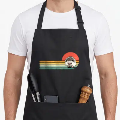 Retro hedgehog animal apron - Hedgehog standing in front of red-orange sun with five horizontal stripes in yellow teal — shown on a black cotton canvas apron against a white background