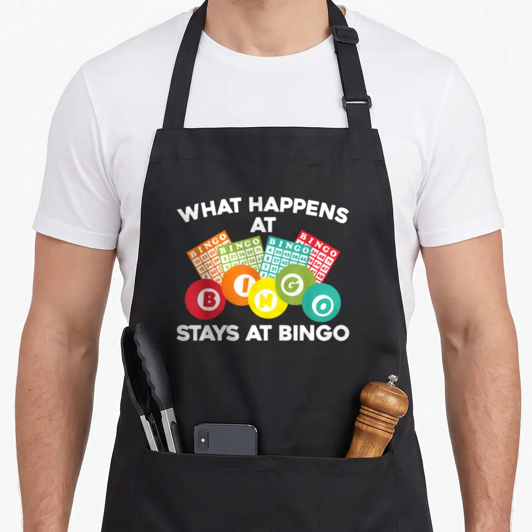 Gambling bingo aprons - White text surrounding five colorful bingo balls and four fanned bingo cards — shown on a black cotton canvas apron against a white background