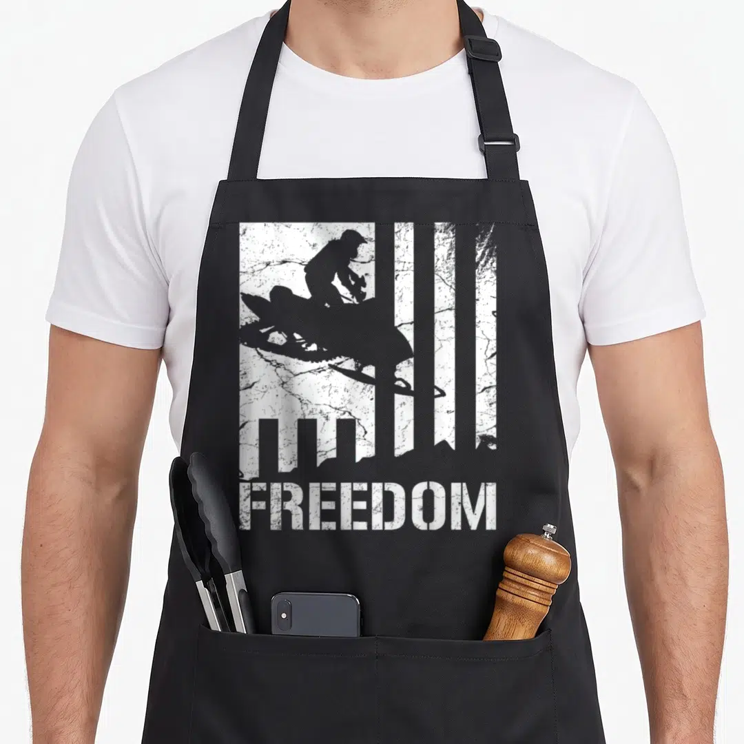 Snowmobiling snowmobile girl apron - White FREEDOM text below vertical stripes and snowmobile rider silhouette — shown on a black cotton canvas apron against a white background