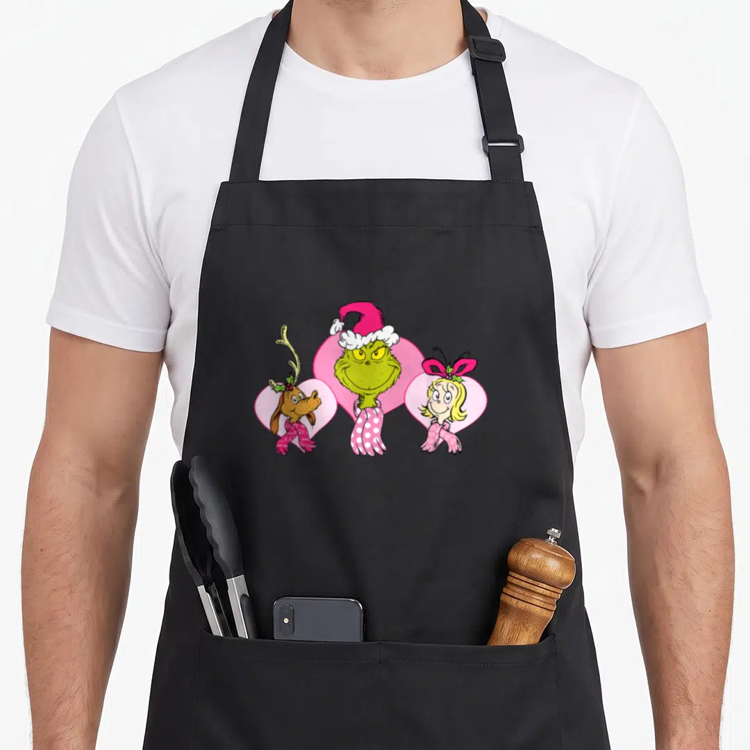 Max cindy lou who apron - The Grinch Max and Cindy Lou Who standing in front of pink hearts in cartoon style — shown on a black cotton canvas apron against a white background