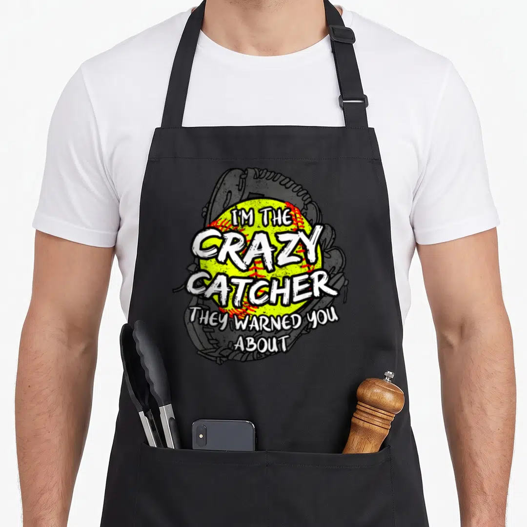 Catcher softball apron - Yellow softball and grey mitt with I'M THE CRAZY CATCHER THEY WARNED YOU ABOUT text — shown on a black cotton canvas apron against a white background