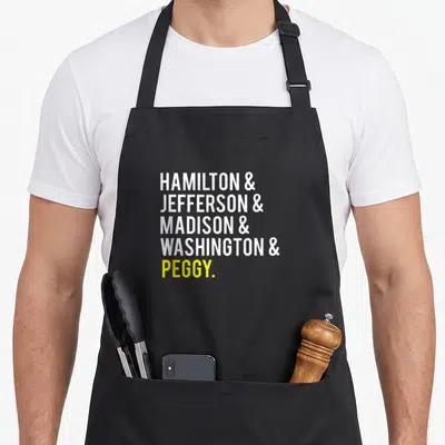 Jefferson hamilton ohio apron - Stacked white and yellow text reading Hamilton Jefferson Madison Washington Peggy — shown on a black cotton canvas apron against a white background