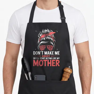 Acting mother's apron - White hair bun with red leopard sunglasses and sarcastic text about mother — shown on a black cotton canvas apron against a white background