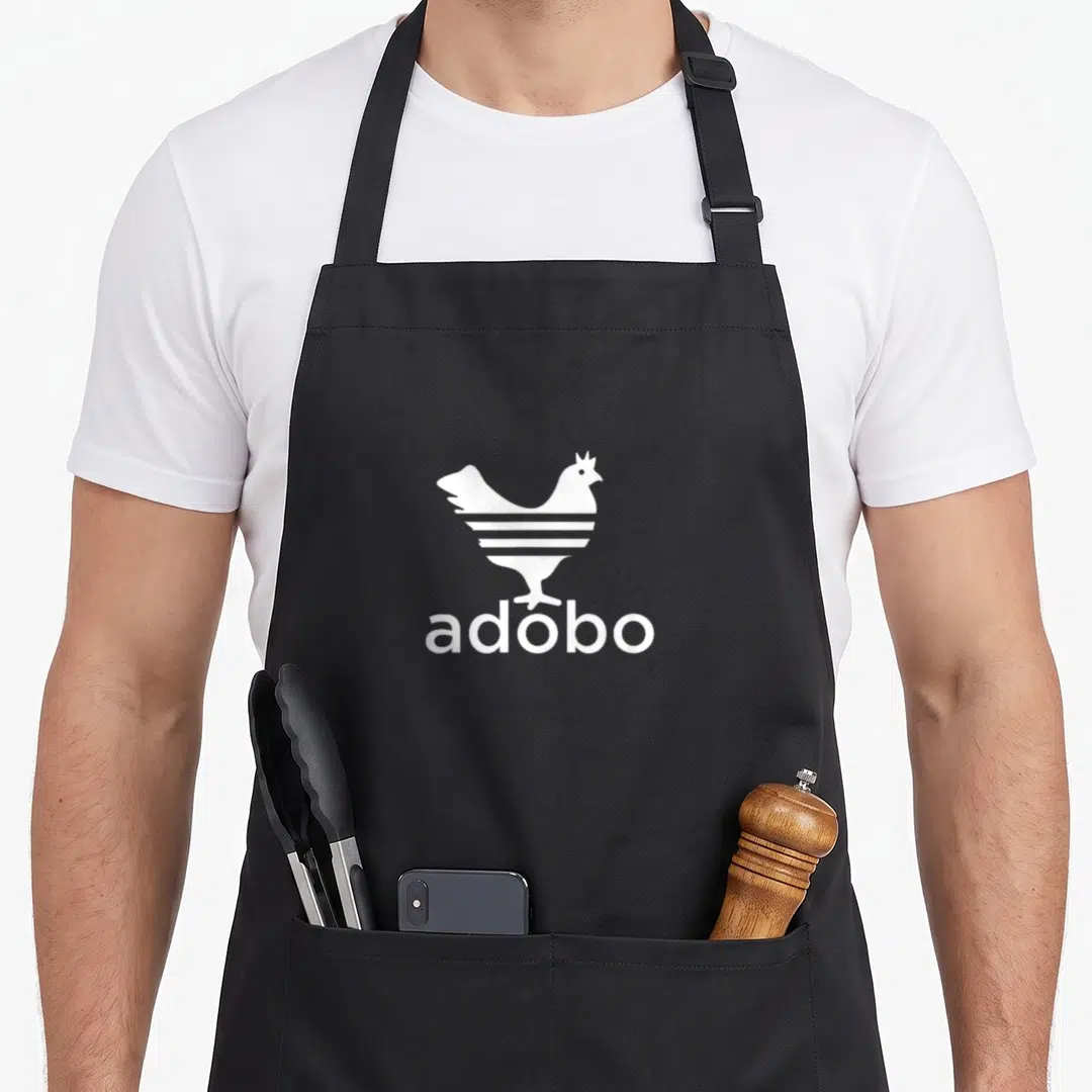 Philippine chicken apron - White striped chicken silhouette above adobo text — shown on a black cotton canvas apron against a white background