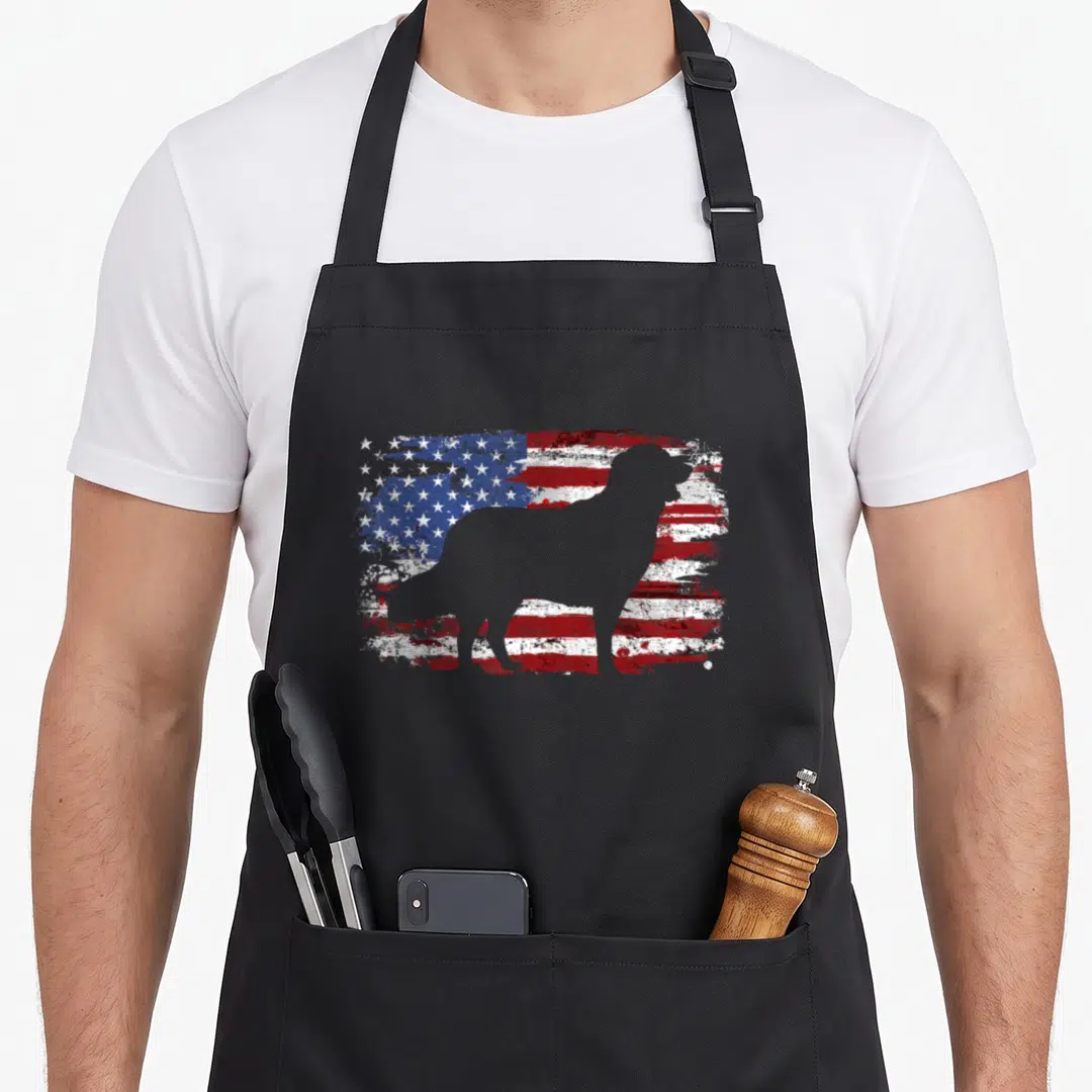 Cute flag golden retriever apron - Grey dog silhouette standing in front of a distressed red white and blue flag — shown on a black cotton canvas apron against a white background