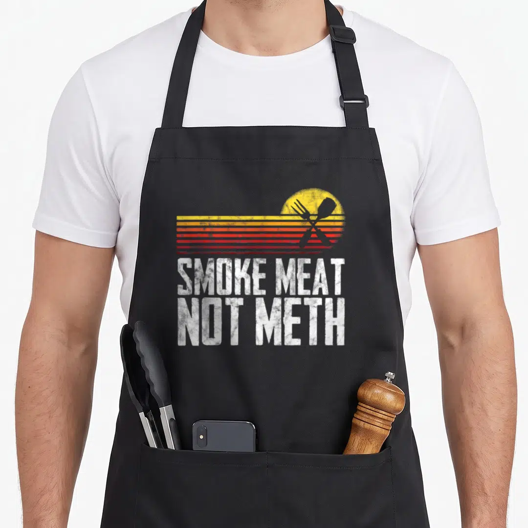 Grilled meat aprons - Retro sun stripes crossed fork spatula Smoke Meat Not Meth text — shown on a black cotton canvas apron against a white background