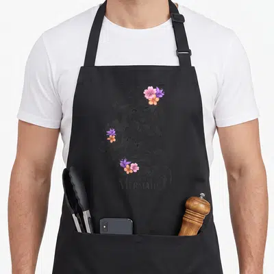 Line floral apron - Grey line-art mermaid with pink purple orange flowers in hair and centered text below — shown on a black cotton canvas apron against a white background