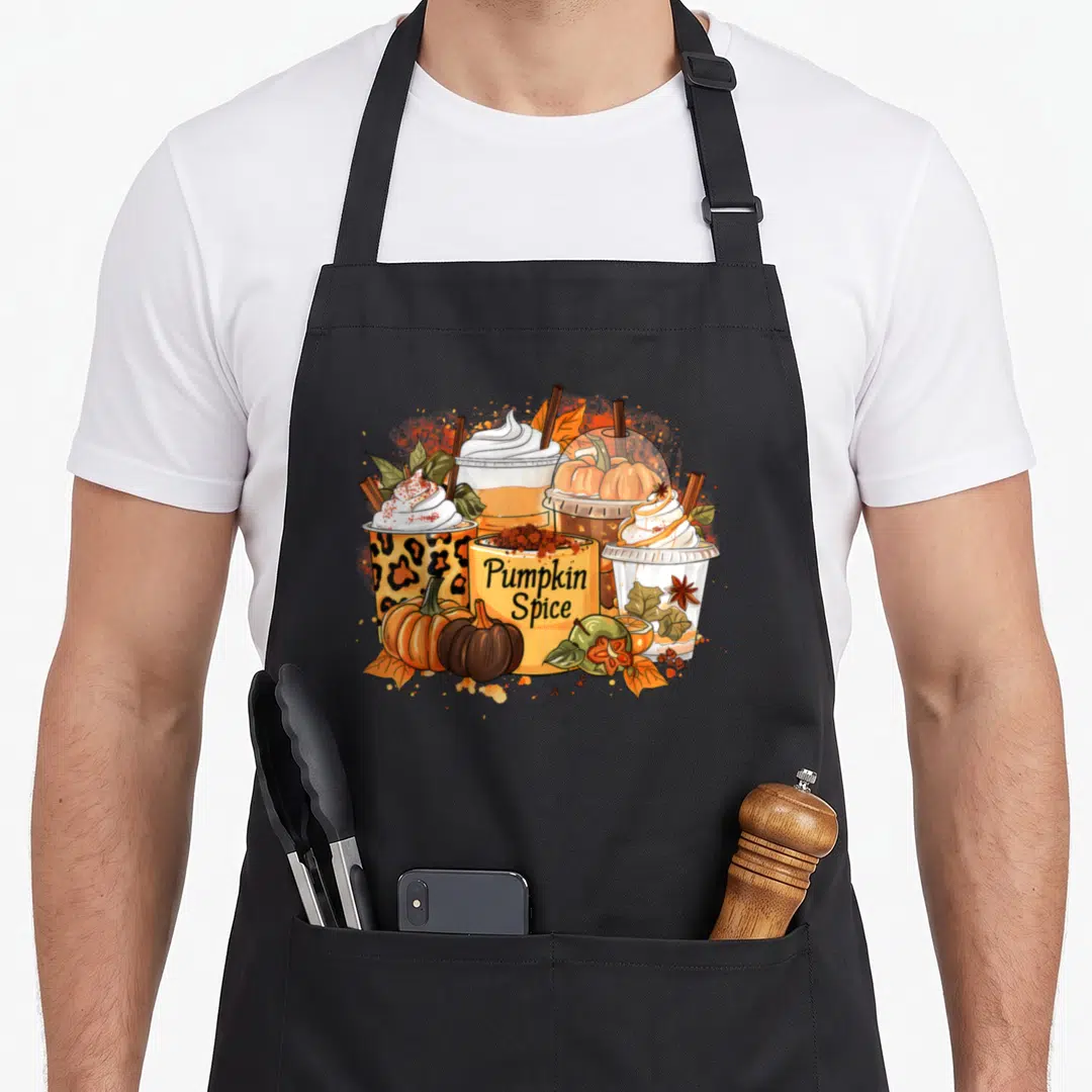 Season thanksgiving apron - Cartoon cluster of three pumpkin spice drinks, spice container, pumpkins, and leaves — shown on a black cotton canvas apron against a white background