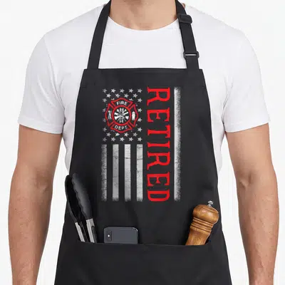 Thin firefighter cooking apron - Distressed flag print with fire dept emblem and vertical RETIRED text in red and white — shown on a black cotton canvas apron against a white background