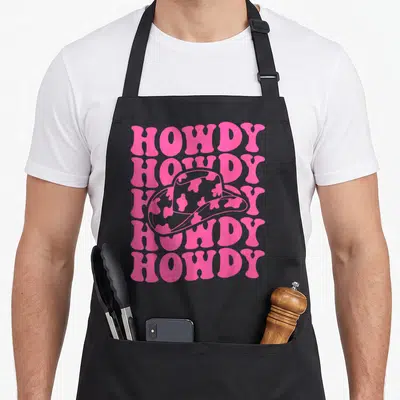 Rodeo southern aprons - Pink stacked HOWDY text with cow-print cowboy hat on grey background — shown on a black cotton canvas apron against a white background