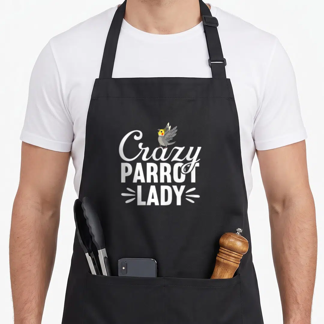 Vintage cockatiel crazy parrot lady apron - Cartoon cockatiel perched on stacked white text reading Crazy PARROT LADY — shown on a black cotton canvas apron against a white background