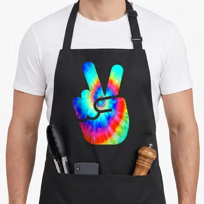 Hand tie apron - Tie-dye hand making a peace sign in blue red yellow green purple — shown on a black cotton canvas apron against a white background