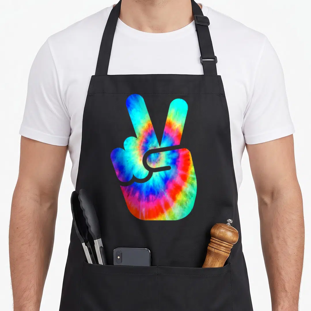 Hand tie apron - Tie-dye hand making a peace sign in blue red yellow green purple — shown on a black cotton canvas apron against a white background