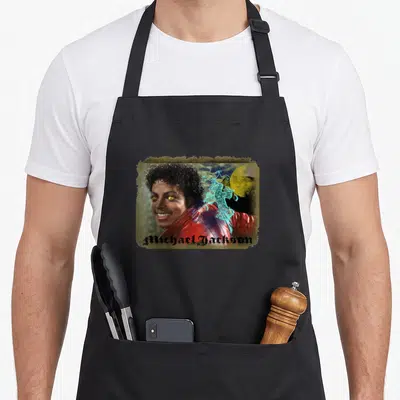 Funny thriller michaels apron - Michael Jackson photo with glowing yellow eyes, blue ornamental cross, yellow moon — shown on a black cotton canvas apron against a white background