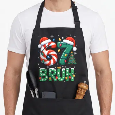 Seven christmas apron - Cartoon 67 wearing Santa hats wrapped in lights with BRUH text below — shown on a black cotton canvas apron against a white background