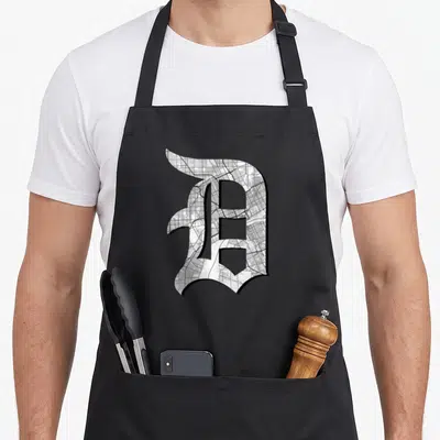 Detroit road apron - Gothic letter D filled with city map pattern in white grey and black — shown on a black cotton canvas apron against a white background