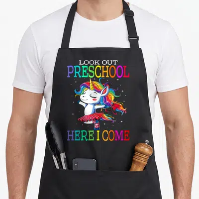 Come preschool apron - Rainbow text Look Out Preschool Here I Come around a dancing unicorn in a tutu — shown on a black cotton canvas apron against a white background