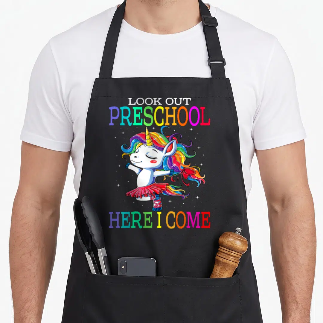 Come preschool apron - Rainbow text Look Out Preschool Here I Come around a dancing unicorn in a tutu — shown on a black cotton canvas apron against a white background