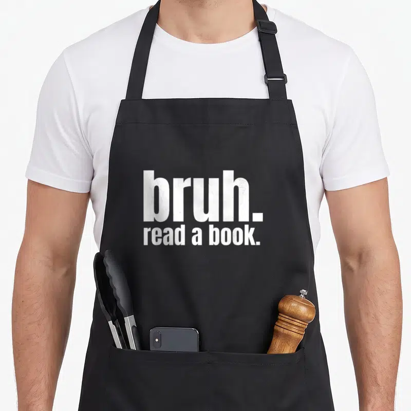 Literature teacher apron - White stacked text bruh. read a book. typography on dark background — shown on a black cotton canvas apron against a white background